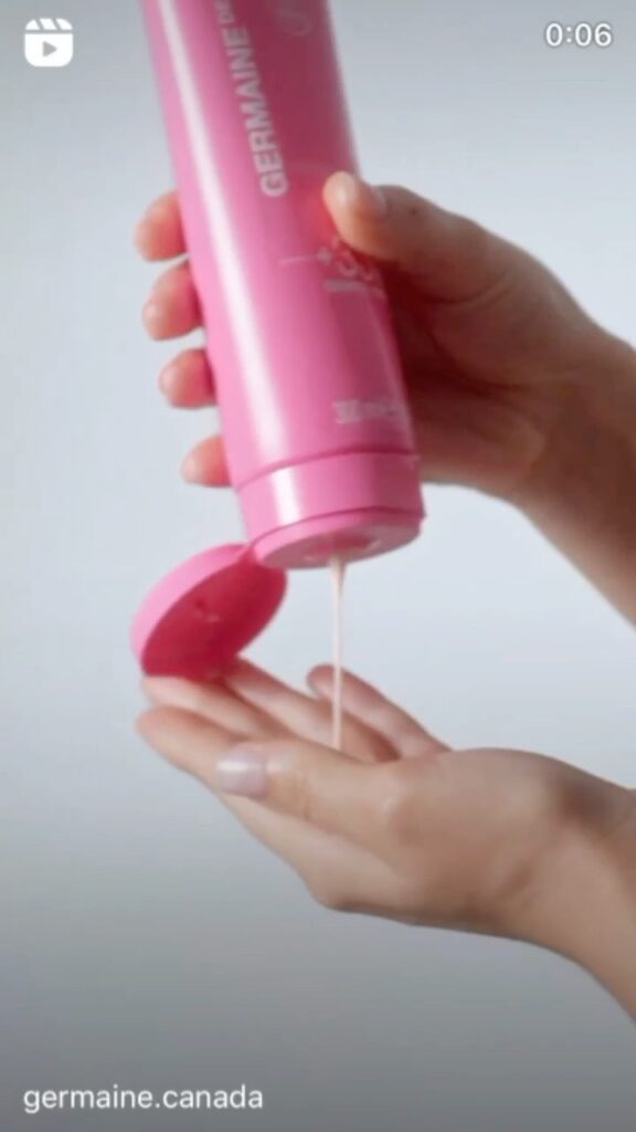 Pink lotion bottle dispensing onto hand